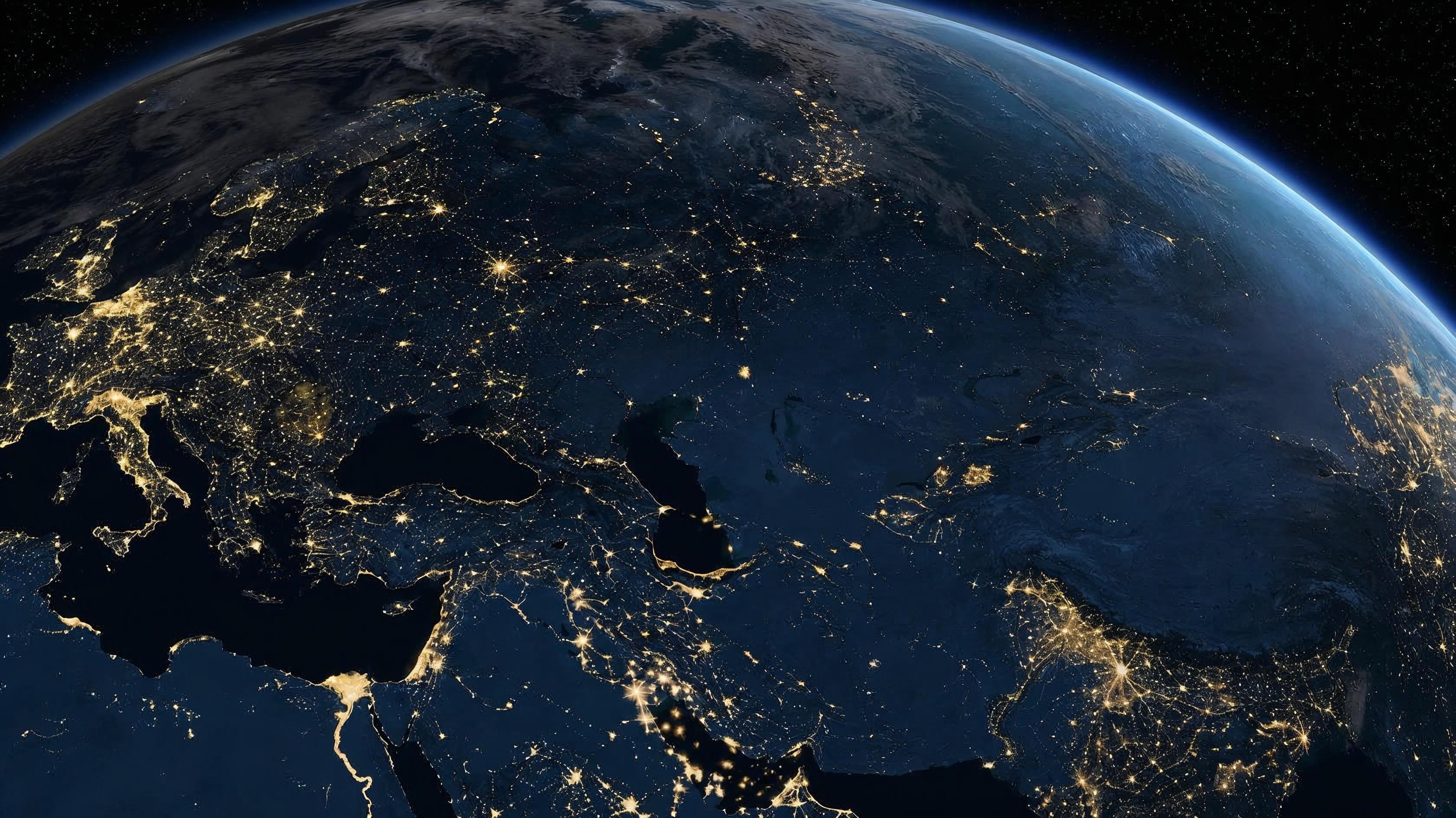 Night view of Earth from space showing Europe and Asia connected by city lights